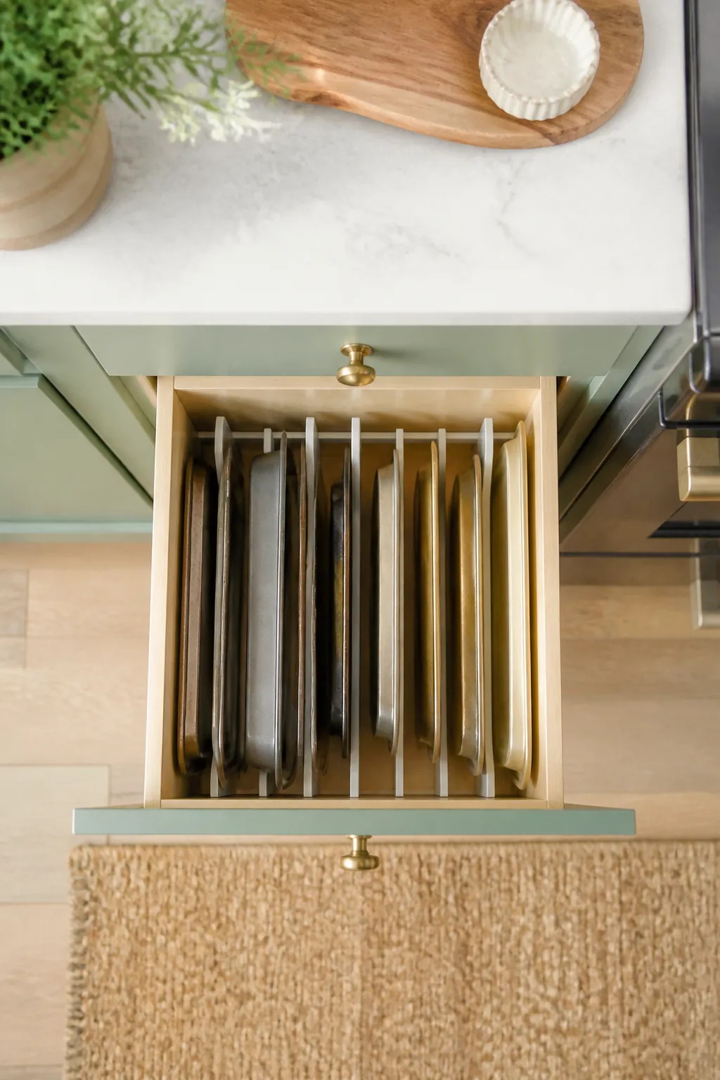 Baking sheets standing upright in a vertical pan rack inside a kitchen base cabinet