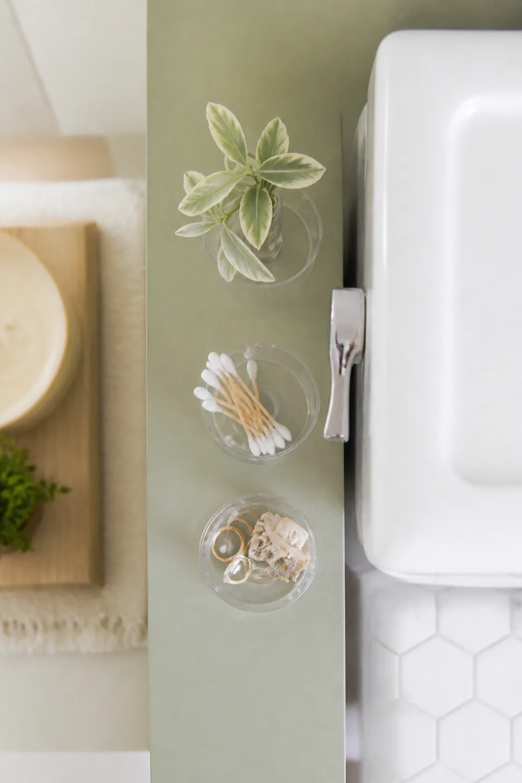 Adhesive cups on the narrow strip of wall beside a toilet tank holding small items