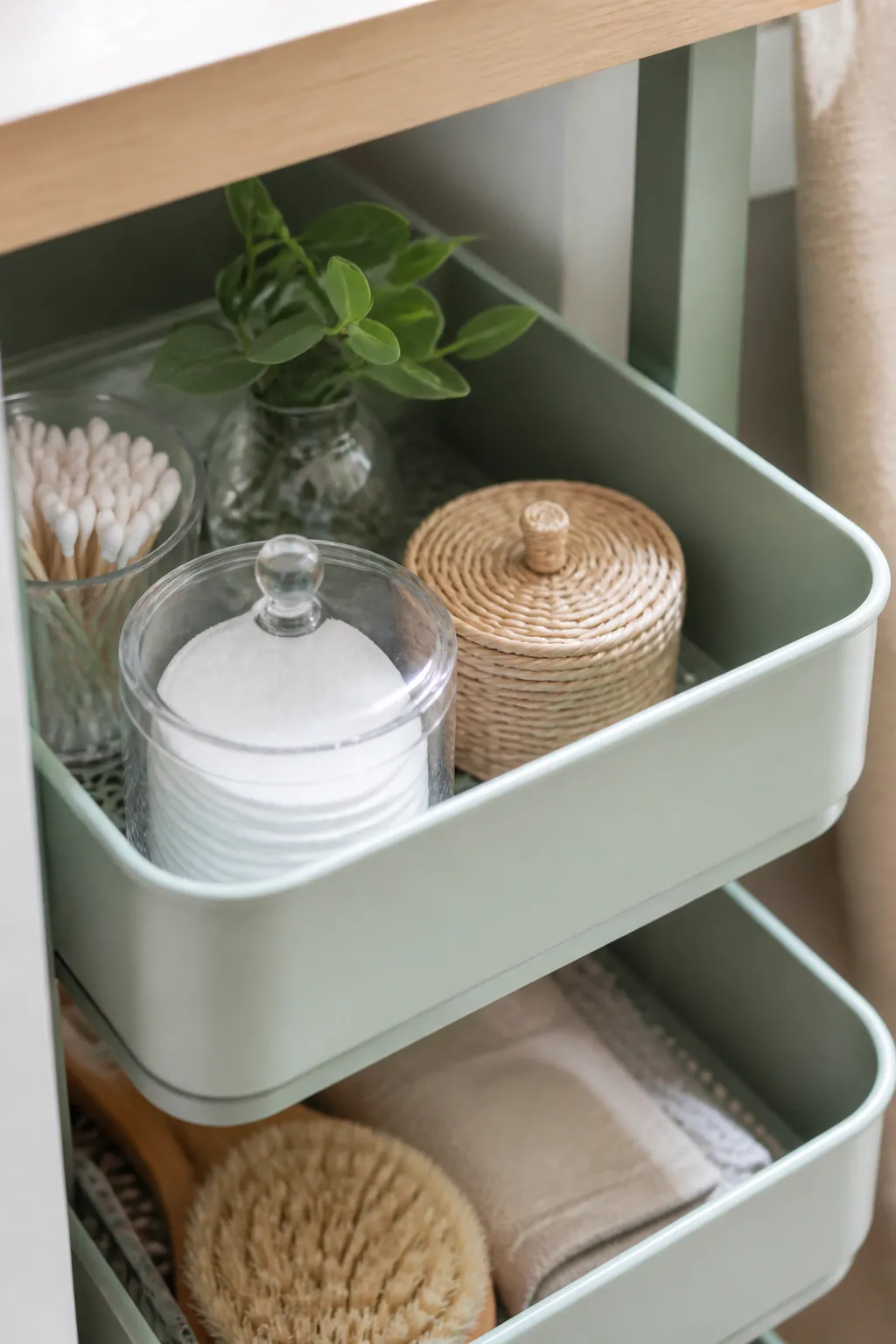 A narrow three-tier rolling cart tucked beside the pipe under a tall open vanity
