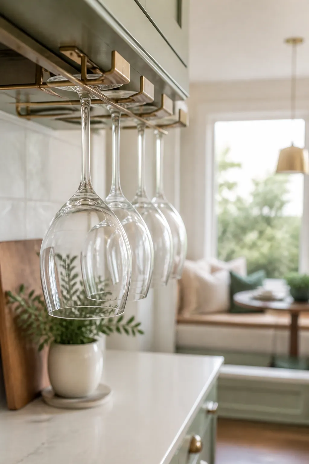 Wine glasses hang stem-up, bowls down, from a holder mounted beneath a kitchen wall cabinet.